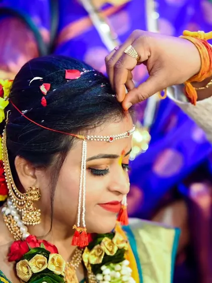 A close-up of the groom applying sindoor to the bride's forehead, a deeply symbolic ritual of marriage.