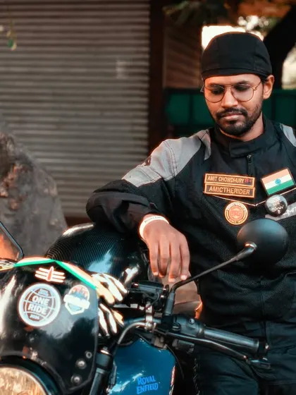 A classic rider portrait. This individual, leaning against his bike, exudes a calm confidence. The photo highlights his riding gear and the patches that signify his belonging to the biker community.