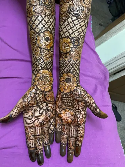 This floral-themed bridal design covers the hands and arms in a dense pattern of roses and jaal work. The inclusion of the bride's name on the palm adds a lovely personal touch.