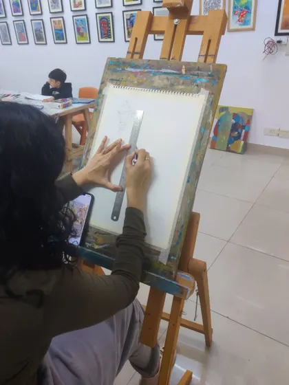 A student uses a ruler to ensure straight lines in the initial drawing phase of an architectural watercolor piece, highlighting the importance of precision.