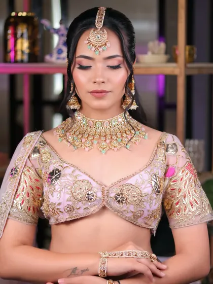 A serene and graceful pose highlighting the complete pastel look, from the maang tikka to the soft, blended makeup.