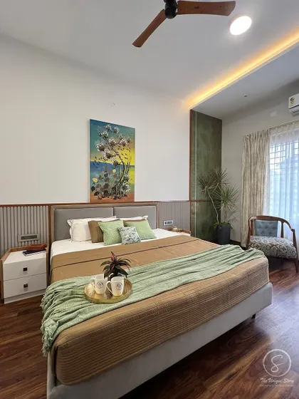 A wider view of the earthy master bedroom, showing the fluted wood paneling behind the bed and a large piece of nature-inspired art. The wooden floors and ceiling fan complete the warm, organic feel.