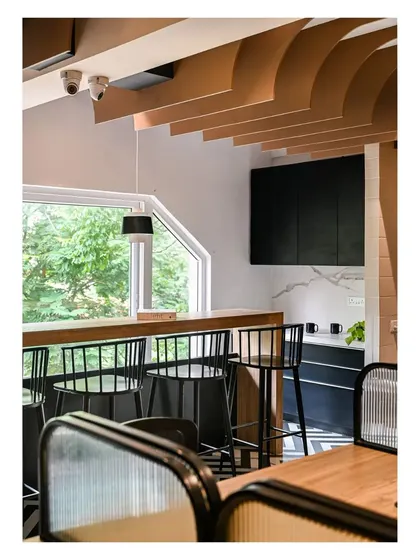 The compact pantry and dining area feature a high-top counter with bar stools, overlooking a large window. The design is simple, functional, and bright.
