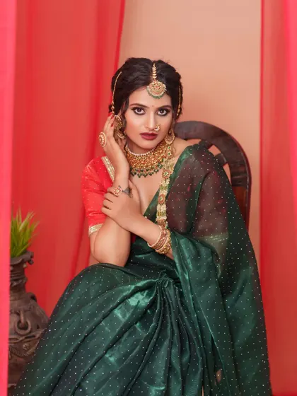 A powerful and regal portrait in the dark green organza saree. The traditional jewellery and classic drape create a look of timeless elegance.
