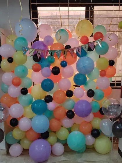 A balloon wall is a fantastic way to create a fun and colorful photo backdrop for any event. This welcome party setup uses a vibrant mix of pastel and bright balloons to build a dense, eye-catching feature wall.