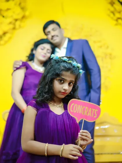 A family portrait with a young girl in a purple gown holding a "Congrats" prop, perfect for celebrating a special occasion.
