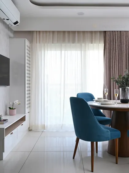 This view shows the dining area in relation to the TV and puja unit, demonstrating how we can create distinct zones in an open-plan layout while maintaining a cohesive design.