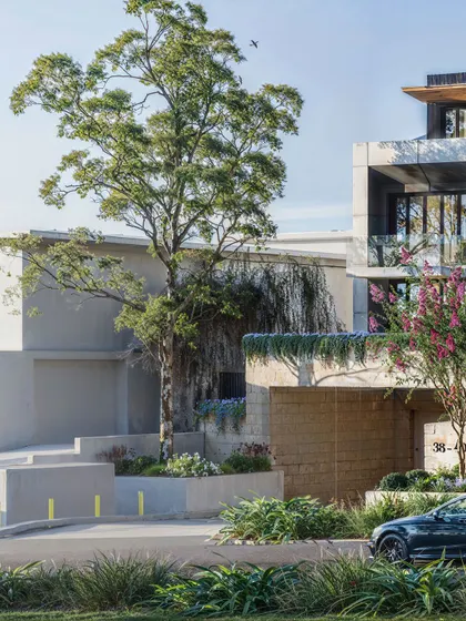 The entrance to a modern apartment building, featuring a distinctive waterfall wall and carefully selected plantings that create a memorable first impression.