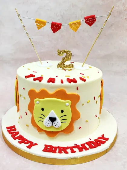 We celebrate a little cub's birthday with this cheerful cartoon lion cake. A friendly lion face, festive bunting, and a glittering number "2" candle make this a bold and playful centerpiece for a jungle-themed party.