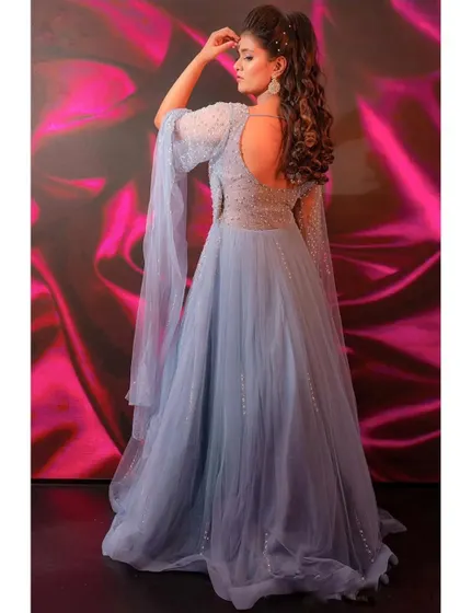 A gown that's pure magic from every angle. The backless design and flowing cape sleeves of this powder blue ball gown create an ethereal and unforgettable look.