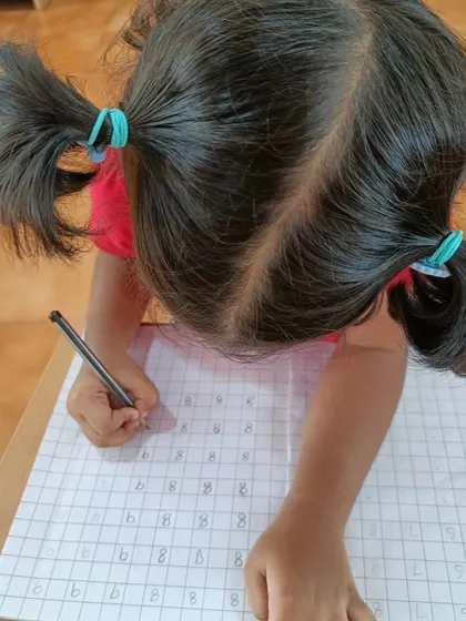 With intense focus, a child practices writing numbers. The repetition helps build muscle memory and confidence in her ability to form the symbols correctly.