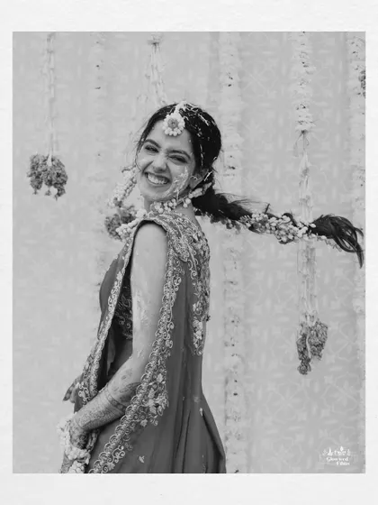 A beautiful black and white portrait of the bride, her face lit up with a joyful smile, even while covered in Haldi.