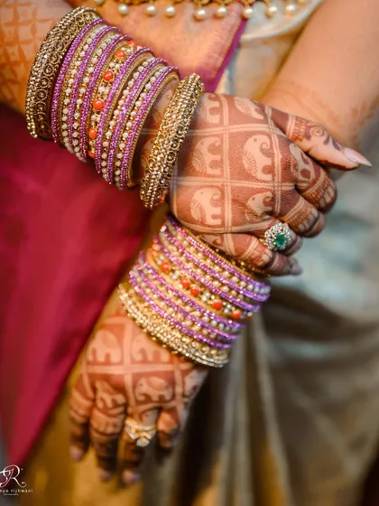 A close-up of the bride's hands, showing her intricate mehendi and colorful bangles.