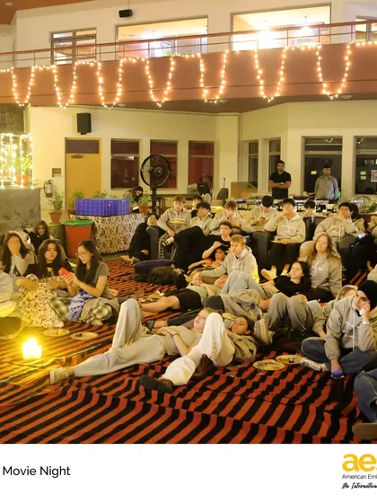 Seniors get comfortable on floor cushions and beanbags for a relaxing movie night. Events like these help build a strong sense of community and celebrate the friendships made during their time at AES.