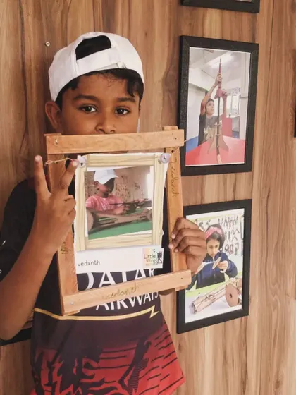A student proudly displays the rustic wooden photo frame he built himself during our woodworking camp.
