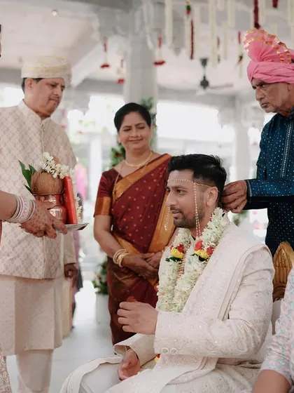 A candid shot of the groom during a pre-wedding ritual, surrounded by his family.