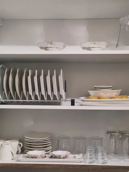 A simple and effective crockery cabinet setup. A vertical plate rack and neatly arranged glasses and mugs make this space highly functional.