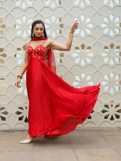 This image showcases the elegant flow of the red anarkali, with the model's makeup looking polished and camera ready.