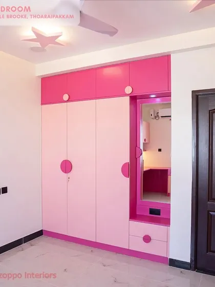 A fun and vibrant kids' bedroom at Jain's Pebble Brooke, with pink and white wardrobes, circular knobs, and star-shaped ceiling lights.