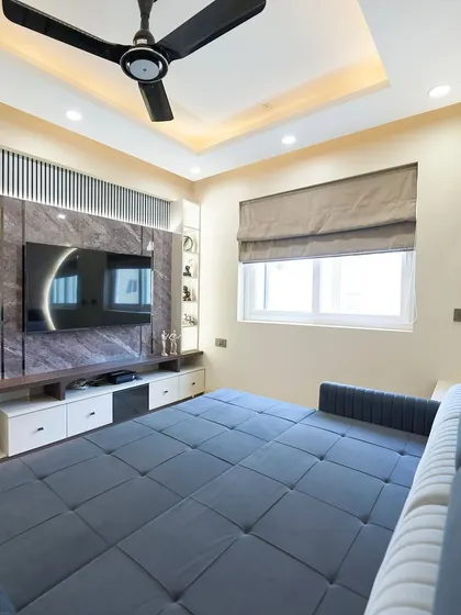 The sofa bed fully extended, showing how the room transforms into a comfortable sleeping space. The marble-paneled TV wall adds a touch of luxury.