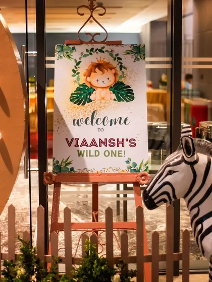 The welcome sign for Viaansh's party, featuring a cute lion cub and tropical leaves. This easel sign, placed at the entrance, warmly greets guests.