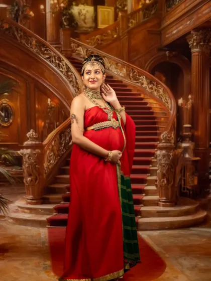 A solo portrait of the queen on a grand staircase, her red and green traditional attire looking magnificent against the opulent backdrop.