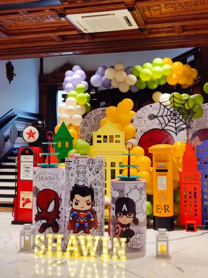 Another view of the superhero party, showing the custom-printed plinths with chibi-style Spider-Man, Superman, and Captain America. Every element is designed to be cohesive and on-theme.