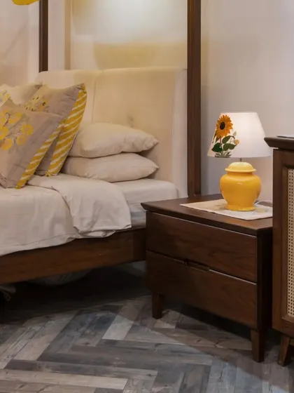 The bedside table, crafted from the same warm wood as the four-poster bed, features clean lines and a rattan-fronted drawer, continuing the theme of natural materials and timeless design.
