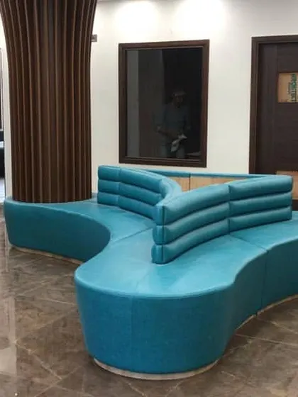 This custom-designed, free-form sofa serves as the centerpiece of the school's reception waiting area. Its unique shape encourages interaction while the teal upholstery adds a vibrant touch to the space.