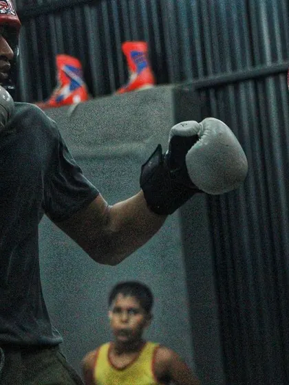A young fighter watches intently as two senior members spar. Learning happens both inside and outside the ropes.
