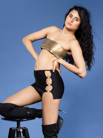A seated pose in a gold top and boots, with a strong and confident attitude.