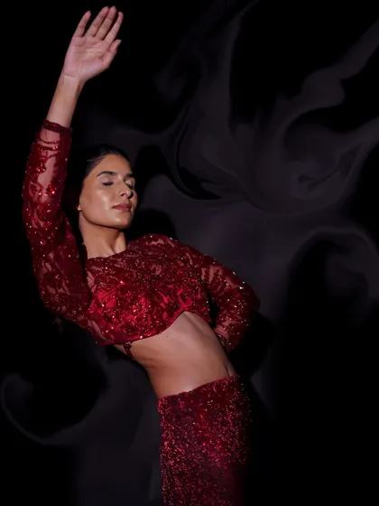 An expressive, artistic shot where the model's movement and the smoky background effect complement the ruby red dress, creating a powerful and emotional image.