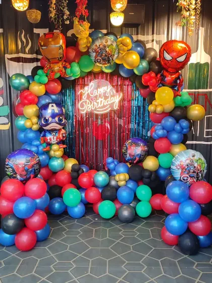 An action-packed Avengers superhero party. This balloon arch features character balloons of Iron Man, Captain America, and Spiderman, set against a red shimmer backdrop with a neon sign.