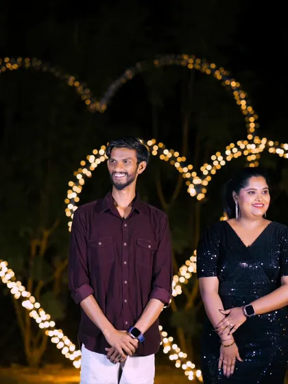 A beautiful night shot with the couple standing before a large, heart-shaped light installation.