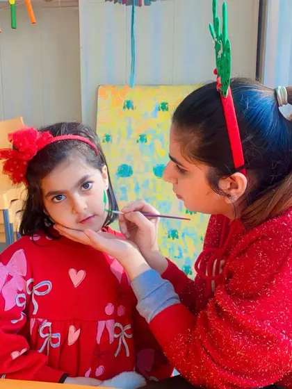 An instructor carefully applies face paint to a child, a popular activity at our special events.