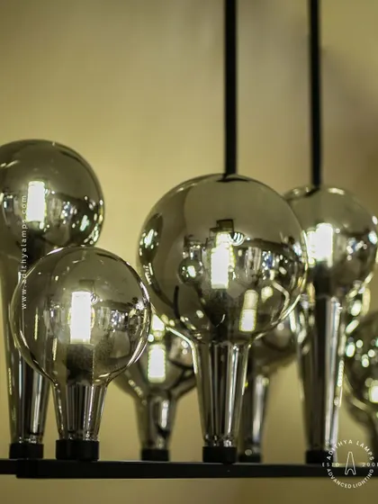 A playful yet chic linear chandelier featuring a series of chrome-finished glass bubbles. The highly reflective surface and modern design make it a striking addition to a kitchen island or a contemporary dining space.