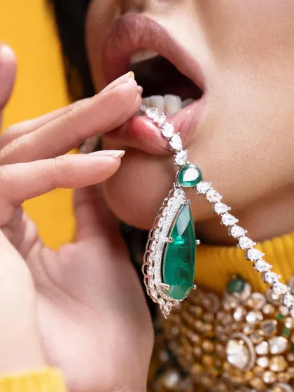 A sensual and provocative close-up, where the emerald pendant is the star. This kind of shot creates a memorable and aspirational image for a jewelry brand.