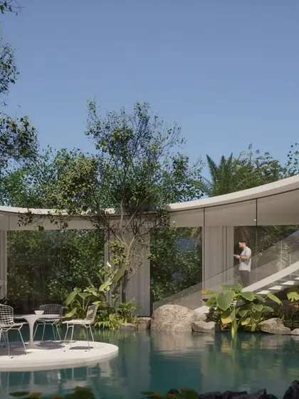 This Vastu-compliant residence in Hyderabad is designed around a central courtyard with a water body. A curved staircase acts as a sculptural focal point, and expansive glass walls connect the interior spaces to the lush, tropical-inspired landscape.