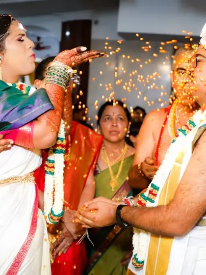 A playful moment during the Akshata ritual. The bride's expression and the flying rice grains create a dynamic and fun photograph that captures the spirit of the celebration.