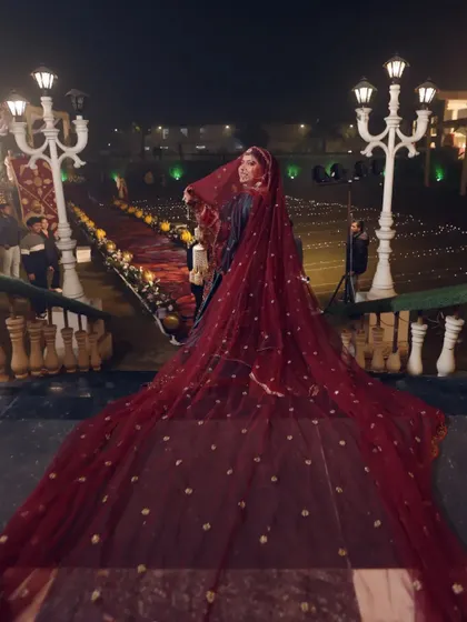 A grand, full-length shot of the bride with her long, flowing red veil creating a dramatic and royal entrance.
