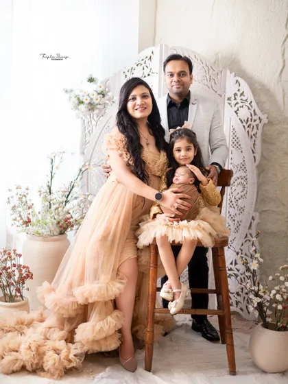 A lovely family portrait celebrating the arrival of a newborn. The older sister proudly holds her new baby sibling, showcasing a beautiful family moment.