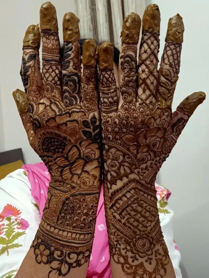 This image captures the fresh application of a very dense bridal mehendi. The dark paste covers the hands and arms completely, promising a wonderfully deep stain.