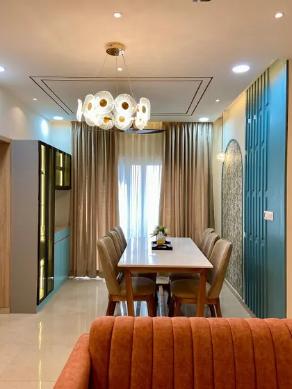 This dining room is designed for sophisticated entertaining, featuring a large marble-top table, plush beige chairs, and a stunning modern chandelier that serves as a piece of art.