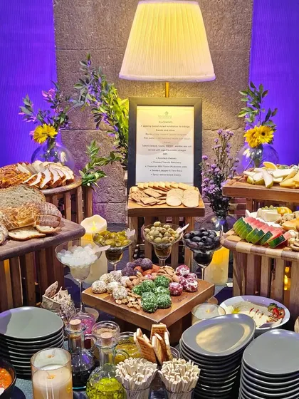 A look at our lavish tapas grazing experience curated for a Mercedes-Benz and tequila soirée. The table is filled with artisanal breads, cheeses, olives, and dips, creating an abundant and inviting centerpiece for guests.