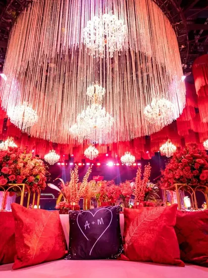 A view from the main couple's sofa, showcasing their personalized monogrammed cushion. This vantage point looks out towards the grand stage and the magnificent ceiling of chandeliers and tassels.