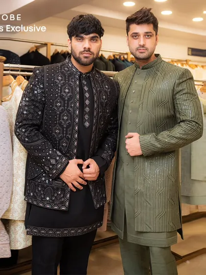 Two styles, one vibe. Models showcasing a black embroidered Indo-western and an olive green textured sherwani, perfect for coordinating with your friends.
