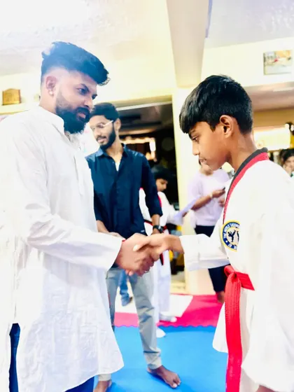 A handshake and congratulations for a student who has earned his red belt.