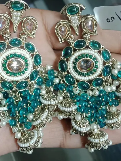 Heavy and grand jhumka earrings with green stones and beadwork. These are perfect for a bridal look or for anyone who loves large, traditional earrings.