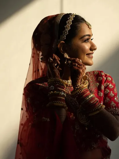 The golden hour light hitting the bride's henna is just magical. This photo beautifully captures the details of the henna design as she adjusts her veil.
