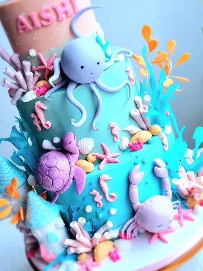 A vibrant, multi-tiered underwater cake. This design is packed with sculpted sea creatures like an octopus, turtle, crab, and whale, all made from fondant.